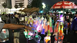 Pedagang menjual terompet pada malam pergantian tahun di kawasan Bundaran HI, Jakarta, Senin (31/12). Pergantian tahun dimanfaatkan pedagang untuk mencari keuntungan dengan berjualan pernak pernik tahun baru.(Liputan6.com/Angga Yuniar)