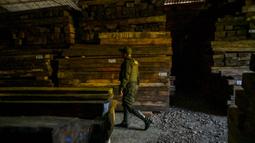 Seorang petugas polisi menunjukkan kayu ilegal di sebuah gudang di kotamadya Socorro, Santader, Kolombia, pada 3 Desember 2023. (Juan BARRETO/AFP)