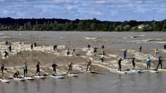 Sejumlah warga berselancar di Sungai Dordogne, Saint-Pardon, Prancis (24/7). Fenomena pasang surut besar yang menyebabkan gelombang arus di Sungai Dordogne ini dimanfaatkan warga dan turis unutk berselancar. (AFP Photo/Georges Gobet)