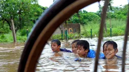 Hujan yang turun sejak Minggu (8/2) lalu, mengakibatkan kawasan perumahan mewah Garaharaya di Tangerang, Banten terendam air setinggi lebih kurang 90 cm. Tampak sejumlah bocah asyik bermain air, Selasa (10/2/2015). (Liputan6.com/Faisal R Syam)