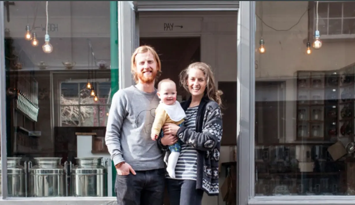 Richard Eckersley bersama keluarga kecilnya befoto didepan toko ramah lingkungan miliknya di Devon, Inggris. Di toko tersebut, dia mengharuskan para pelanggan membawa keranjang sendiri. (Bola.com/Instagram Earthfoodlove)