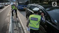 Anggota Kepolisian Korps Lalu lintas melakukan penindakan tilang manual kepada pengendara yang nekat melintasi jalur busway di Jakarta, Selasa (16/5/2023). (Liputan6.com/Faizal Fanani)