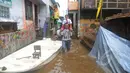Seorang warga menggendong anaknya melewati banjir di kawasan Kampung Pulo, Jatinegara, Jakarta Timur, Selasa (10/2/2015). Warga tetap beraktivitas meski harus menembus banjir yang melanda pemukiman mereka. (Liputan6.com/Herman Zakharia)