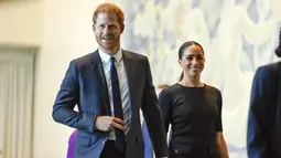 Meghan Markle didampingi suaminya Pangeran Harry tersenyum saat tiba di markas PBB (18/7/2022). Meghan dan Harry tampak kompak mengenakan pakaian serbahitam. (AP Photo/Seth Wenig)