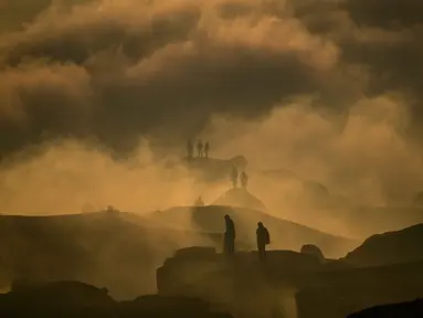 Para penganut Hindu dari komunitas Tengger terlihat melalui awan rendah saat matahari terbit ketika mereka mendaki gunung berapi aktif Bromo untuk mempersembahkan sesaji berupa beras, buah-buahan, ternak, dan barang-barang lainnya sebagai bagian dari festival Yadnya Kasada di Probolinggo, Jawa Timur, Senin 1 Juni 2026. (JUNI KRISWANTO/AFP)