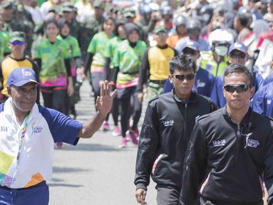 Legenda taekwondo Indonesia, Abdul Rojak, membawa obor Asian Games saat melintasi di Banjarmasin, Kalimantan Selatan, Senin (30/7/2018). Sebanyak 53 kota di Indonesia akan dilalui oleh obor Asian Games. (Bola.com/Reza Bachtiar)
