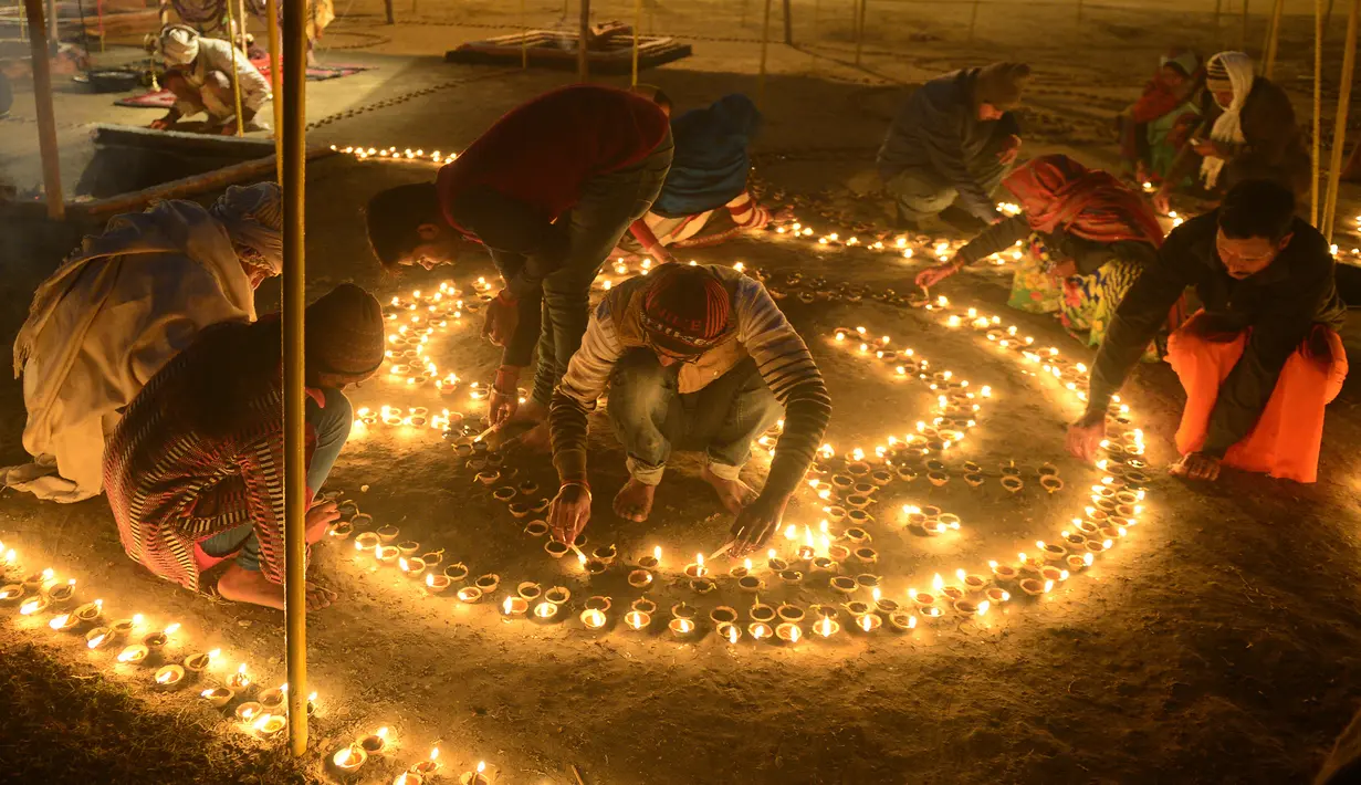 Umat Hindu India menyalakan lampu minyak untuk perayaan tradisional Magh Mela di Sangam, India (2/1). Magh Mela adalah sebuah festival tahunan yang digelar umat Hindu di India. (AFP Photo/Sanjay Kanojia)