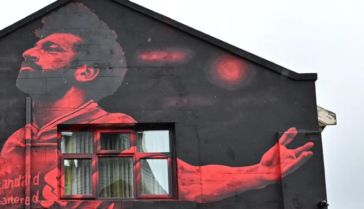 Mural seniman Inggris, John Culshaw yang menggambarkan pesepak bola Mesir Mohamed Salah dilukis di fasad bangunan dekat Stadion Anfield, di Liverpool, Rabu (30/3/2022). Mohamed Salah tidak diragukan lagi, adalah salah satu pemain terhebat yang pernah mengenakan seragam Liverpool. (Paul ELLIS / AFP)