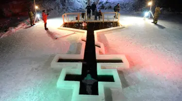 Penganut Kristen Ortodoks terjun ke kolam air es selama perayaan liburan Epiphany di Desa Tyarlevo di luar Saint Petersburg, Rusia, Kamis (18/1). (Olga MALTSEVA/AFP)