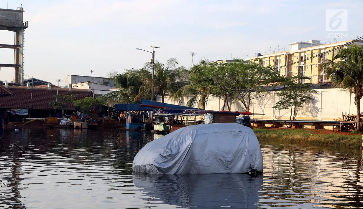 Sebuah mobil terparkir di jalanan yang terendam banjir rob di kawasan Muara Baru, Penjaringan, Jakarta Utara, Kamis (7/12). Rob tinggi membuat tanggul tidak mampu menahan air laut sehingga membanjiri jalanan. (Liputan6.com/Johan Tallo)