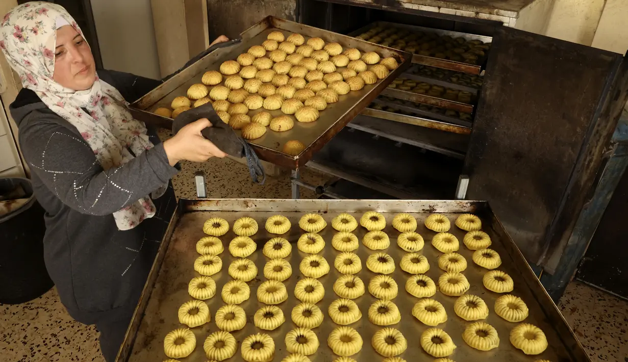 <p>Perempuan Palestina membuat kue tradisional berisi kurma dan kacang-kacangan dalam persiapan untuk liburan Idul Fitri, di kota Hebron, Tepi Barat, pada 28 April 2022. Seluruh umat Muslim di dunia akan menandai berakhirnya bulan suci Ramadhan dengan Idul Fitri. (HAZEM BADER / AFP)</p>