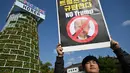 Seorang pengunjuk rasa Korea Selatan memegang plakat saat unjuk rasa mengecam tekanan Presiden AS Donald Trump untuk meningkatkan investasi Korea Selatan di AS, di Gyeongju pada 29 Oktober 2025, menjelang KTT Kerja Sama Ekonomi Asia-Pasifik (APEC). (Jung Yeon-je/AFP)