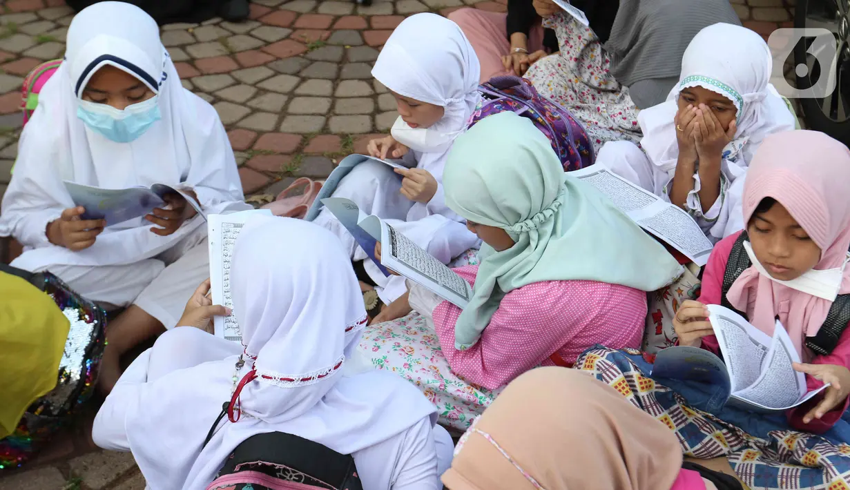 Anak-anak membaca Al-Quran sambil menunggu waktu berbuka puasa di halaman Masjid Raya Jakarta Islamic Center, Jakarta Utara, Senin (18/4/2022). Acara ngabuburit sambil khataman Al-Quran ini merupakan rangkaian acara menyambut 17 Ramadhan atau malam Nuzulul Quran. (Liputan6.com/Herman Zakharia)