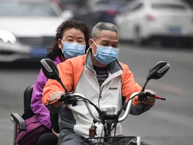 Suami-istri mengenakan masker mengendarai kendaraannya di jalan pada hari yang tercemar polusi udara di Beijing, China (2/4). (AFP Photo/Fred Dufour)