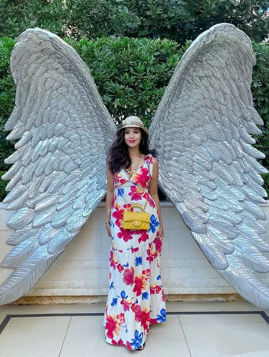 Bintang serial Warkop Millenium ini tampil cetar dengan dress floral cerah senada dengan lipstik yang memoles bibirnya. Topi bundar, tas kuning dan perhiasan emas juga melengkapi gaya khasnya. Latar belakang sayap membuatnya bak ibu peri yang turun ke bumi. (Liputan6.com/IG/@dps_diahpermatasari)