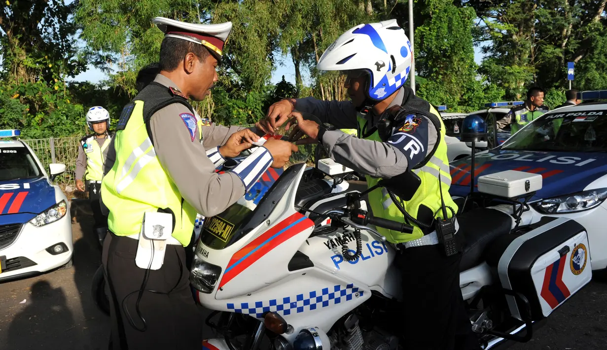 Polisi menempelkan stiker bendera Indonesia dan Arab Saudi selama persiapan menyambut Raja Arab Saudi Salman bin Abdulaziz,Nusa Dua, Bali (2/3). Raja Salman dan rombongan yang terdiri dari 1.500 orang berlibur di Bali. (AFP Photo / Sonny Tumbelaka)