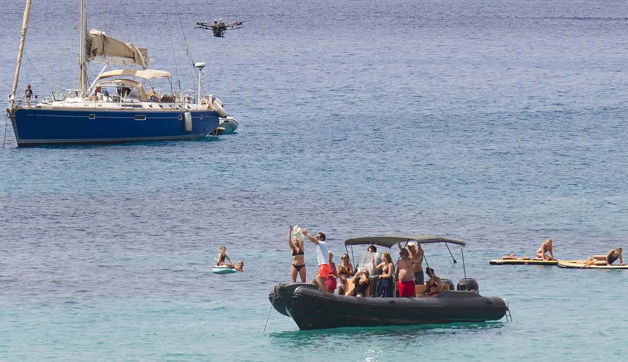Sebuah drone membawa sekantong makanan dari Cala Tadira dekat Sant Josep de Sa Talaia di Pulau Ibiza, Spanyol, 24 Agustus 2021. Restoran Can Yucas dan perusahaan Galicia Aerocamaras meluncurkan layanan Drone to Yacht untuk mengirim makanan dan minuman eksklusif ke kapal pesiar. (JAIME REINA/AFP)