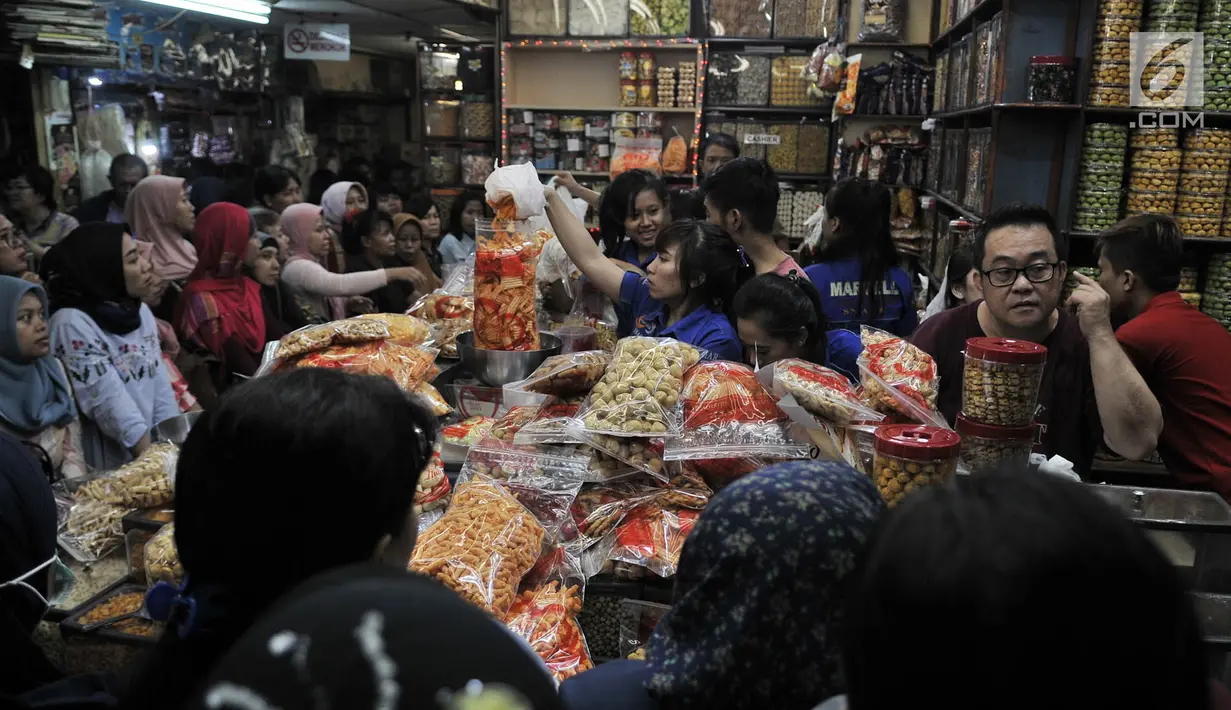 Pedagang melayani pembeli kue kering untuk kebutuhan Lebaran di Pasar Jatinegara, Jakarta, Selasa (5/6). Kue panganan khas Idul Fitri tersebut dibanderol mulai dari Rp 40 ribu hingga Rp 200 ribu per kilogram. (Merdeka.com/ Iqbal S. Nugroho)