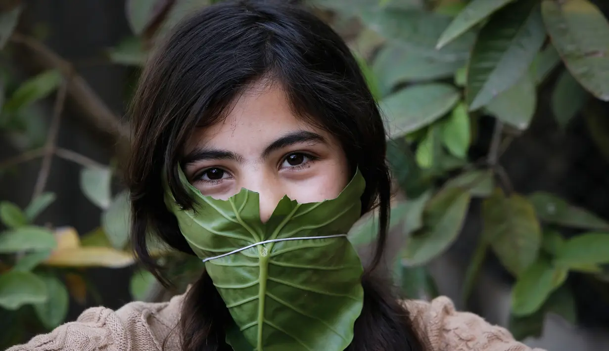 Seorang anak berpose dengan masker yang terbuat dari kubis saat dihibur oleh ibu mereka selama pandemi corona (Covid-19) di Beit Lahia di Jalur Gaza utara (16/4/2020). (AFP/Mohamed Abed)