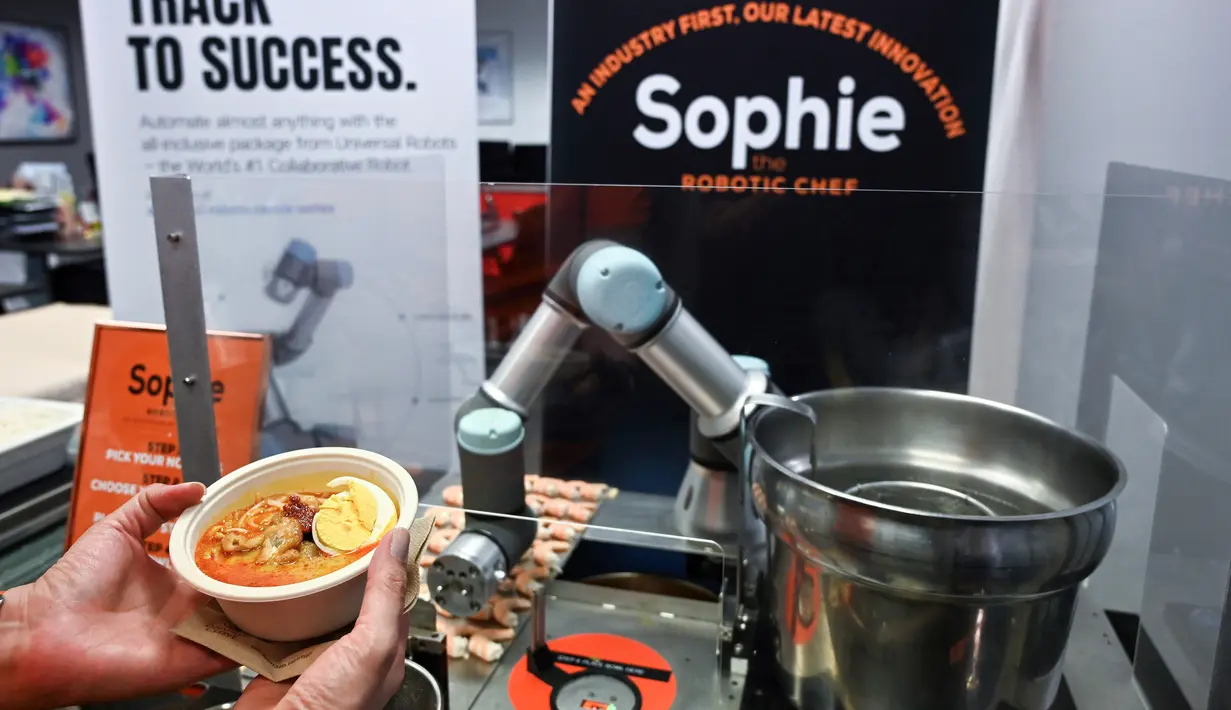 Robot koki bernama Sophie meracik semangkuk laksa saat demonstrasi memasak di Singapura pada 26 Juli 2019. Untuk memesan laksa ini, calon pembeli cukup memilih jenis mie yang diinginkan dan tambahannya seperti potongan ikan olahan dan toge. (Roslan RAHMAN / AFP)