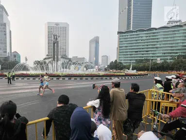 Warga menyaksikan lomba lari maraton putri Asian Games 2018 di kawasan MH Thamrin, Jakarta, Minggu (26/8). Meski Car Free Day ditiadakan, warga Ibu Kota tetap memadati kawasan MH Thamrin menyaksikan maraton Asian Games 2018. (Merdeka.com/Iqbal S. Nugroho)
