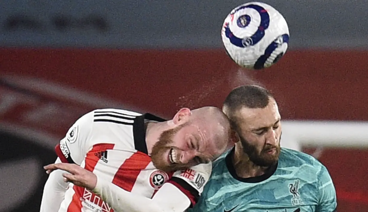 Pemain Liverpool, Nathaniel Phillips, duel udara dengan pemain Sheffield United, Oliver McBurnie, pada laga Liga Inggris di Stadion Bramall Lane, Minggu (28/2/2021). Liverpool menang dengan skor 2-0. (Oli Scarff, Pool via AP)