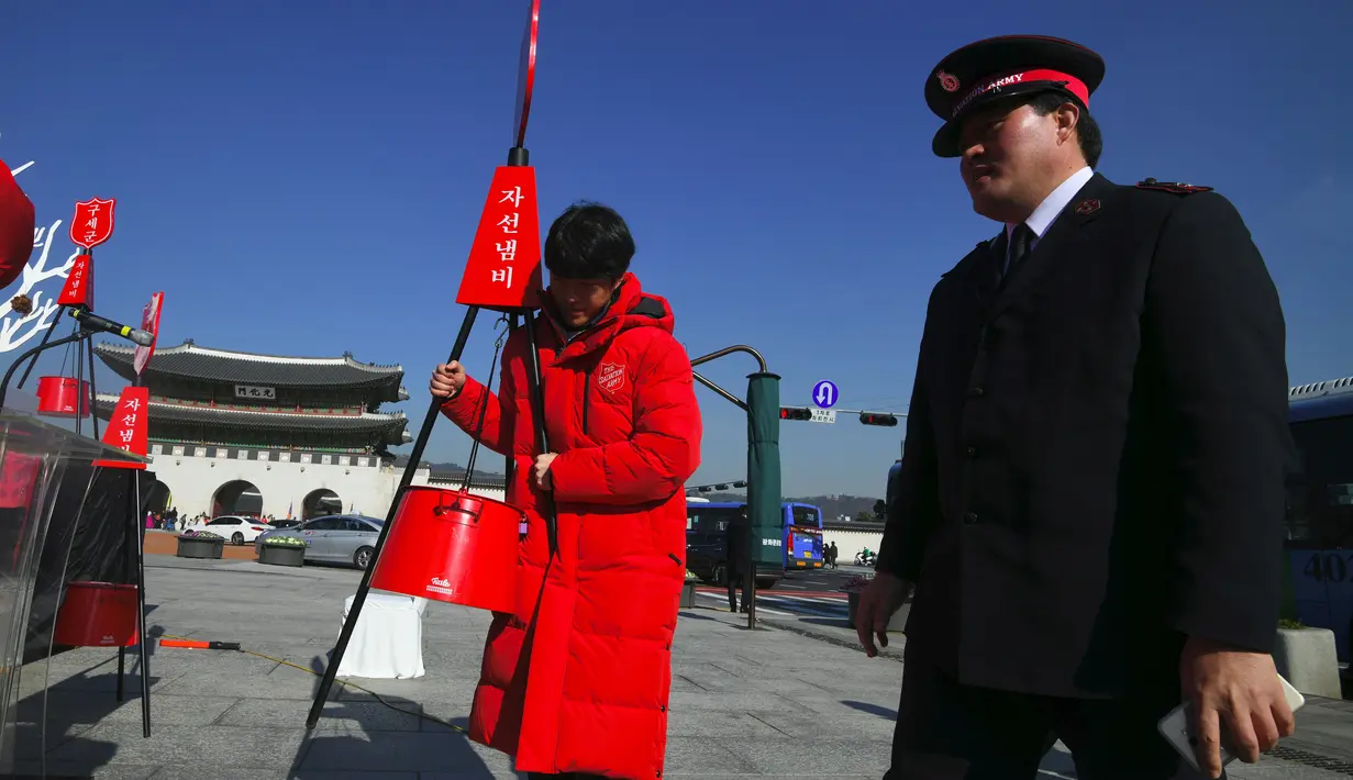 Seorang peserta membawa pot amal dengan mengenakan pakaian Santa Claus saat kampanye penggalangan dana untuk orang miskin di depan Istana Gyeongbokgung, Seoul, Jumat (30/11). (Jung Yeon-je/AFP)