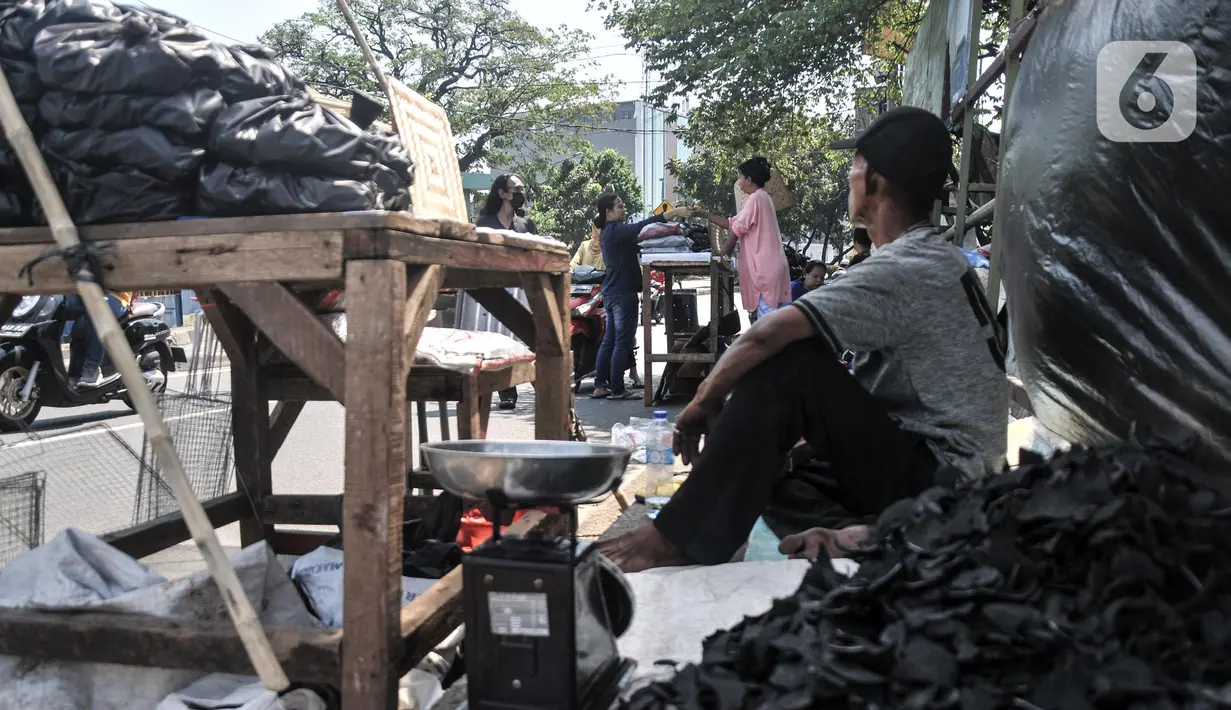 Pedagang arang melayani pembeli di kawasan Manggarai, Jakarta Selatan, Minggu (10/7/2022). Harga arang di tempat ini relatif murah mulai dari Rp 5.000 hingga Rp 25.000 per bungkus. (merdeka.com/Iqbal S. Nugroho)