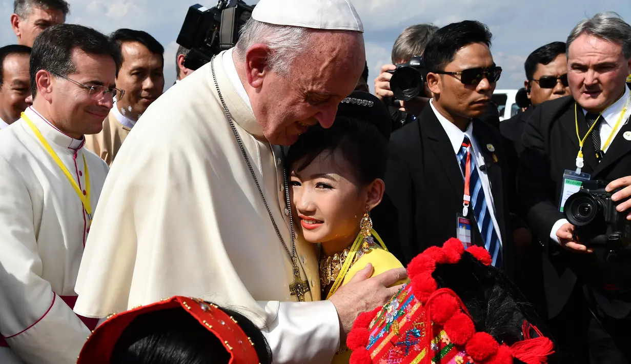 Seorang anak perempuan memeluk Paus Fransiskus saat menyambut kedatangannya di Bandara Internasional Yangon, Myanmar (27/11). Kedatangan Paus Fransiskus disambut oleh ribuan umat Katolik Roma yang memenuhi Yangon. (AFP Photo/Vincenzo Pinto)