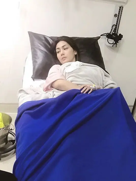 Terlihat dalam foto yang diunggah, Arie, istrinya terlihat lemas dan pucat saat terbaring di ranjang rumah sakit. Di tangannya terlihat ada jarum inpus yang menempel. (Instagram/ariekuntung)