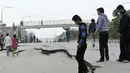 Sejumlah warga di Kathmandu berjalan melintasi jalan yang rusak akibat gempa, Minggu (26/4/2015). Gempa berkekuatan 7,8 Skala Richter dikabarkan telah menelan korban sekitar 2000 jiwa. (AFP Photo/Prakash Mathema)