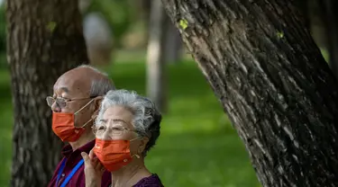 Orang-orang yang memakai masker duduk di bangku di taman umum di Beijing, Jumat (8/7/2022). Ibu kota China, Beijing, tampaknya telah membatalkan rencana untuk mengeluarkan mandat yang mengharuskan orang menunjukkan bukti vaksinasi COVID-19 untuk masuk ke ruang publik tertentu setelah penolakan di kalangan penduduk. (AP Photo/Mark Schiefelbein)