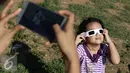 Seorang anak melihat proses gerhana matahari di Bukit Matantimali, Sigi, Sulteng, Rabu (9/3). Fenomena tersebut menjadi daya tarik tersendiri wisatawan untuk menyaksikan secara langsung di alam terbuka. (Liputan6.com/Immanuel Antonius)
