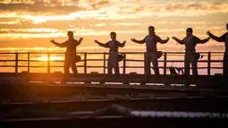 Praktisi Tai Chi melakukan latihan dengan latar belakang matahari terbenam di atas Jembatan Sydney Harbour, Australia, Selasa (2/5). Acara ini diselenggarakan oleh Akademi Tai Chi dan Qigong Australia. (Handout / BRIDGECLIMB SYDNEY / AFP)