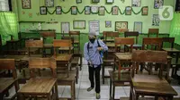 Petugas menyemprotkan disinfektan di kelas SD Negeri Kota Bambu 03/04, Jakarta, Sabtu (21/11/2020). Pemerintah pusat memberikan kewenangan pemerintah daerah membuka sekolah dan melakukan pembelajaran tatap muka pada semester genap tahun ajaran 2020/2021. (Liputan6.com/Faizal Fanani)
