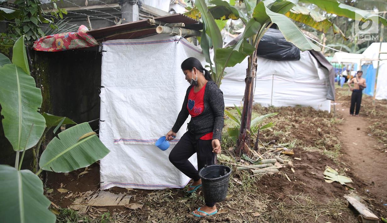 Warga membawa ember berisi air hendakn menggunakan sarana MCK sementara di di Posko Pengungsi Rendang, Bali, Sabtu (2/12). Warga terpaksa memanfaatkan MCK seadanya yang berada di sekitar pengungsian. (Liputan6.com/Immanuel Antonius)