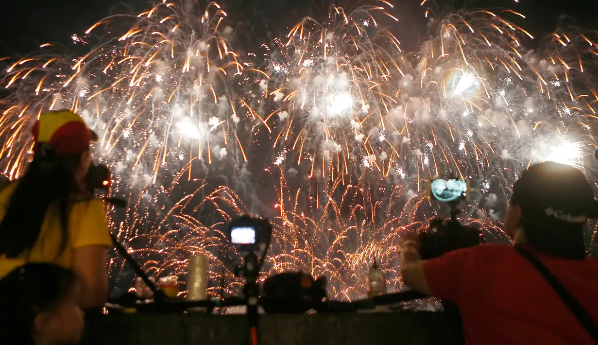 Penonton mengambil gambar pertunjukan kembang api dari Pandora-Pyrotechnie asal Perancis pada Kompetisi Pyromusical Internasional di Manila, Filipina, Sabtu (10/3). Acara yang menarik ribuan wisatawan ini sudah memasuki tahun ke-9. (AP/Bullit Marquez)