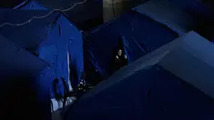 Seorang wanita pengungsi berdiri di samping tenda-tenda yang didirikan di dalam Camille Chamoun Sports City Stadium, yang telah diubah menjadi tempat penampungan bagi orang-orang yang melarikan diri dari serangan udara Israel di Lebanon selatan, Beirut, Lebanon, Rabu 8 April 2026. Serangan Israel yang terus berlanjut memaksa pihak berwenang Lebanon membuka Stadion Camille Chamoun Sports City di Beirut sebagai salah satu lokasi penampungan. (AP Photo/Bilal Hussein)