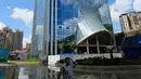 Seorang pria berjalan dekat air terjun yang mengalir di sisi gedung Liebian International Plaza di Kota Guiyang, China, 20 Juli 2018. satu jam pertunjukan air terjun menghabiskan dana tagihan sebesar 118 dollar AS atau sekitar Rp 1,7 juta. (AFP/China OUT)
