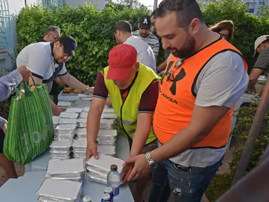 Relawan Tunisia membagikan makanan berbuka puasa gratis selama bulan suci Ramadan di Ariana dekat Tunis (7/5/2020). Masjid-masjid di Aljazair, Maroko dan Tunisia telah ditutup untuk membatasi penyebaran Covid-19, mencegah doa malam khusus. (AFP/Fethi Belad)
