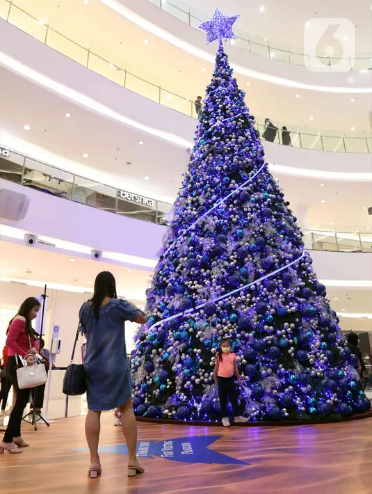 Seorang anak berpose di depan pohon Natal di Senayan City, Jakarta, Senin (14/12/2022). Senayan City menghadirkan Festive Season – The Festive Mood mulai tanggal 12 Desember – 8 Januari 2023, salah satunya Avatar Pandora Experience. (Liputan6.com/Herman Zakharia)
