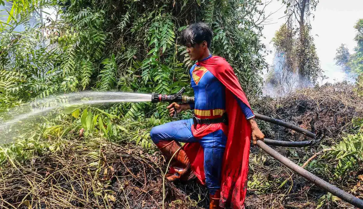 Pelajar bernama Rudiansyah dengan mengenakan kostum Superman membantu memadamkan kebakaran hutan dan lahan di Petuk Katimpun, Palangkaraya, Kalimantan Tengah, 17 Agustus 2026. (AFP/ Reina)