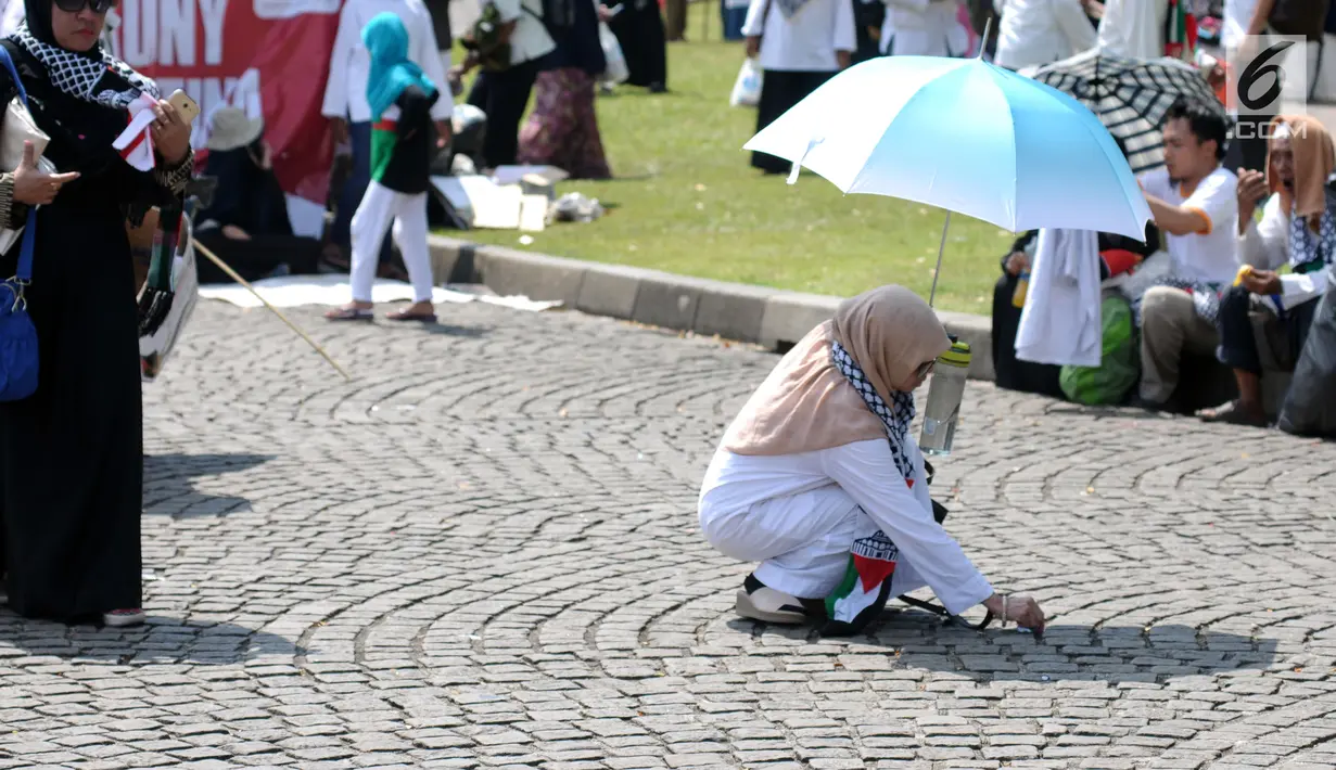 Peserta aksi memunguti ceceran sampah di halaman Monumen Nasional usai aksi, Jakarta, Jumat (11/5). Ribuan massa melakukan aksi menyoroti konflik Palestina dan Israel pada perebutan bangunan suci atau Baitul Maqdis. (Liputan6.com/Helmi Fithriansyah)