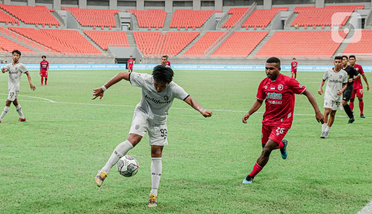 Gelandang Bali United U-18, I Kadek Lanang mengontrol bola dari kawalan bek Indonesia All Stars U-20, Jimmy Julianus pada pertandingan IYC 2021 di Jakarta International Stadium, Jakarta, Selasa (19/4/2022). Indonesia All Stars U-20 menang atas  Bali United U-18 2-1. (Liputan6.com/Faizal Fanani)