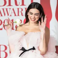 Penyanyi cantik Dua Lipa membawa mawar putih di karpet merah acara Brit Awards 2018, London, Rabu (21/2). Brit Awards dihiasi mawar putih sebagai lambang solidaritas melawan pelecehan seksual yang ramai di industri hiburan. (Vianney Le Caer/Invision/AP)