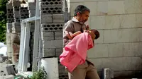 Seorang ayah menggendong anaknya dengan panik di wilayah konflik Yaman (AP/Abdulnasser Alseddik)
