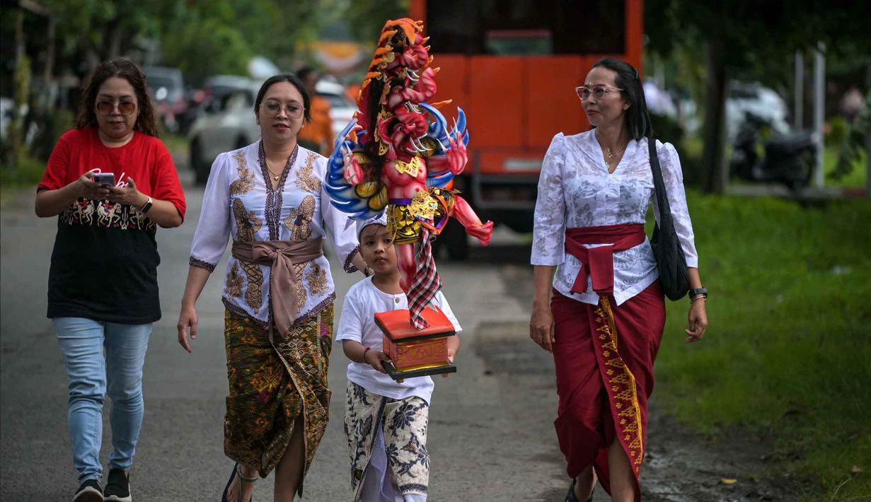 Pura Segara, Kenjeran, Surabaya, pada Rabu (18/3/2026), menjandi salah satu lokasi yang menggelar pawai Ogoh-ogoh. Tampak dalam foto, seorang anak membawa Ogoh-ogoh, patung yang melambangkan roh jahat, selama pawai menjelang Nyepi di Surabaya pada Rabu 18 Maret 2026. (JUNI KRISWANTO/AFP)