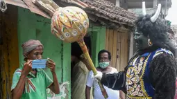 Seorang pria berkostum dewa kematian Yamaraj saat mengimbau warga yang tidak memakai masker di tengah lockdown di Kolkata, India (24/4/2020). (AFP/Dibyangshu Sarkar)