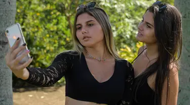 Kembar transgender Brasil, Sofia (kiri) dan Mayla berswafoto di sebuah taman di Campinas, sekitar 100 km dari Sao Paulo, pada 27 Februari 2021. Mayla dan Sofia mengungkapkan mereka tidak pernah nyaman menjadi laki-laki sejak kecil. (Nelson ALMEIDA / AFP)