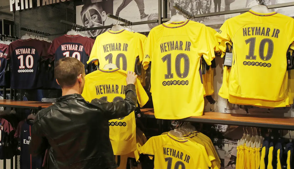 Seorang fans memilih jersey pemain baru Paris Saint Germain, Neymar Jr, di toko merchandise di Paris, Jumat (4/8/2017). Setelah resmi bergabung dengan Paris Saint Germain, jersey Neymar Jr langsung diburu suporter klub Ibu kota. (AP/Michel Euler)